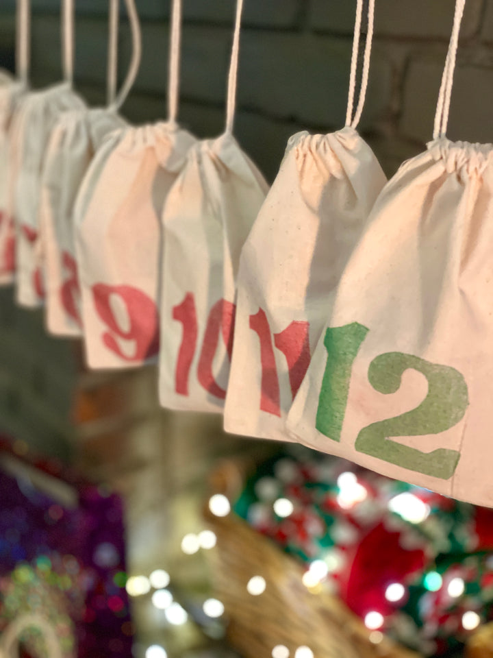 Herbal Tea Advent Calendar in Cotton drawstring bags with custom red stamped numbers. Bags hanging on fireplace mantle. Made by MediTea Wellness.